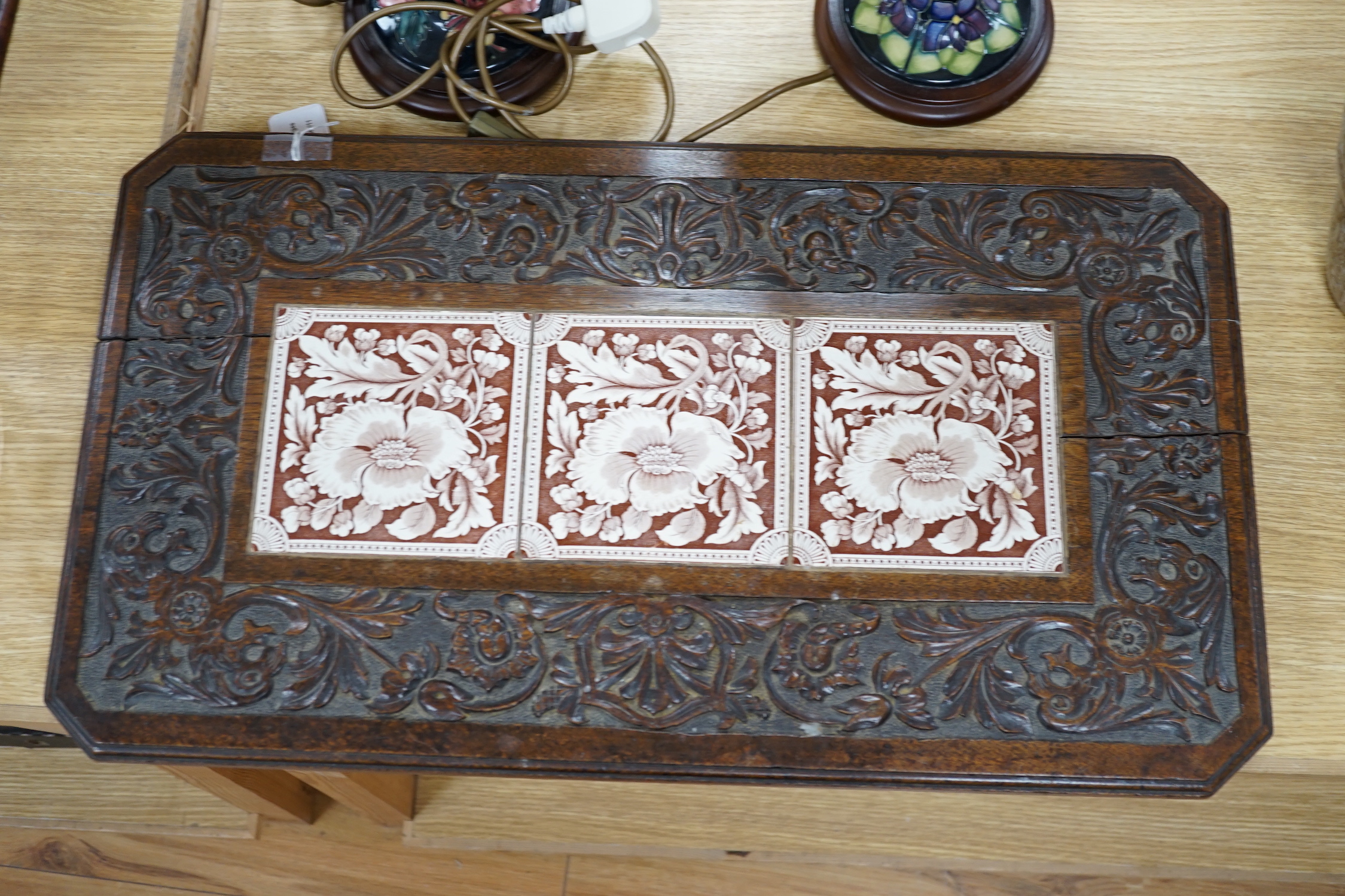 A Victorian carved oak stand inset with there floral tiles, 69cm wide